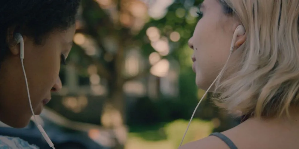 Two people sharing a pair of headphones