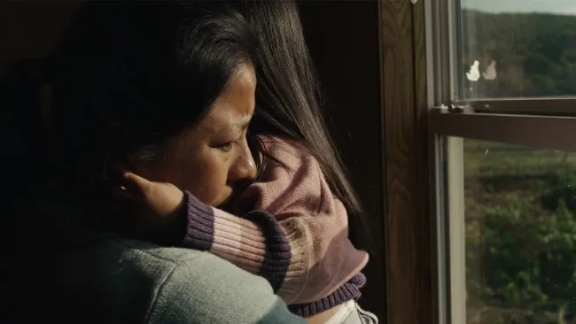 Woman holding a toddler, gazing out the window