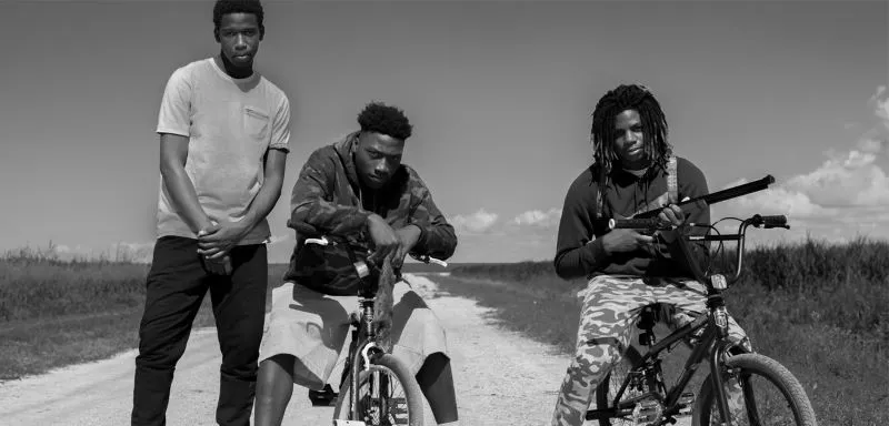 Three men with two bikes on a dirty road