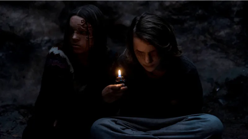 Two people sitting, one is holding a lit lighter