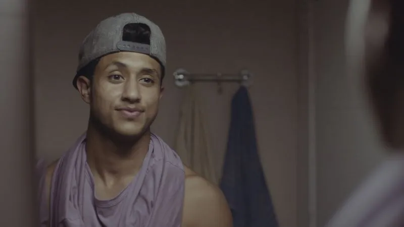 Man with backwards cap looking at himself in mirror