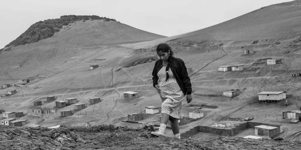 Woman on mountainside with sparse buildings