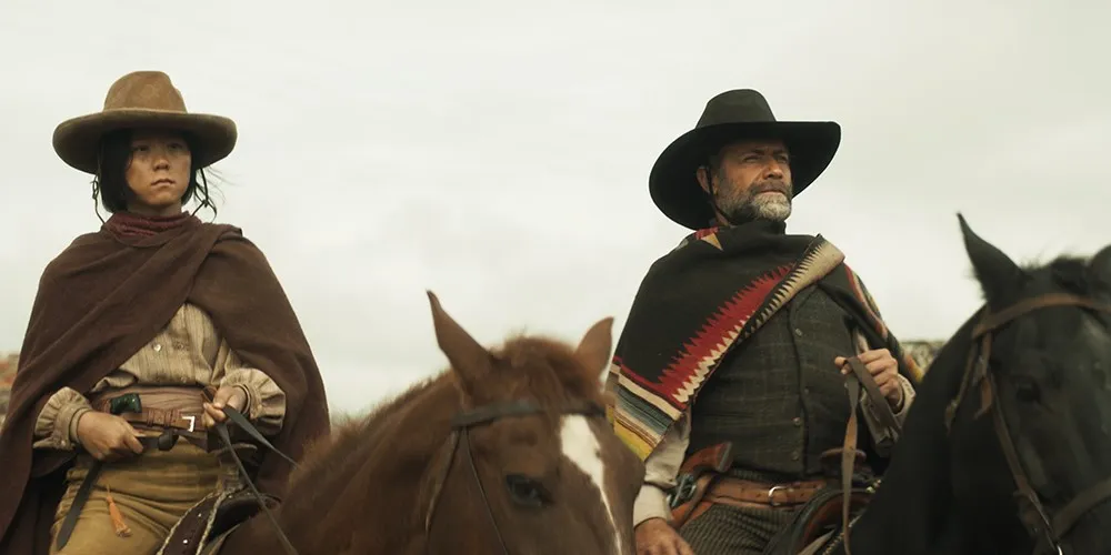Two people in wide-brimmed hats riding horses