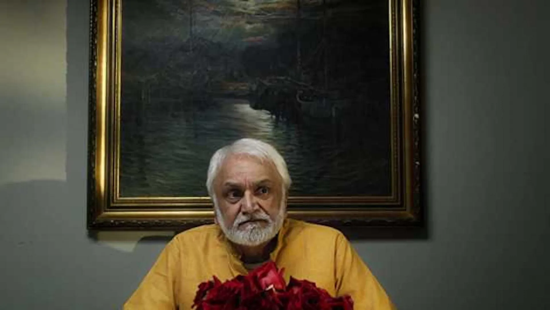 A still from the movie of a man sitting at a table.