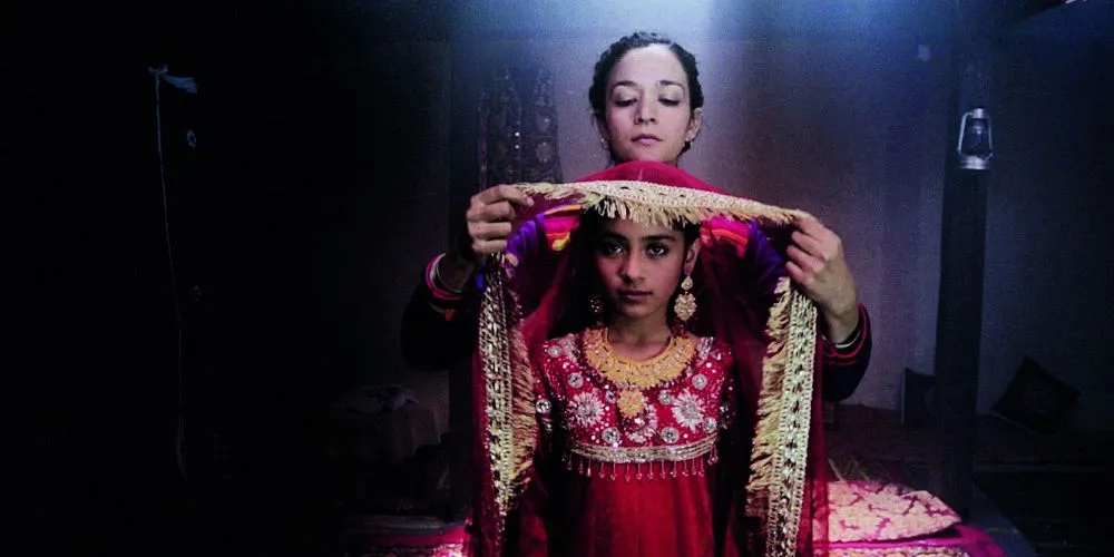 Older woman draping an elaborate textile over the head of a younger woman