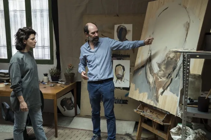 A man shows a painting to a woman.