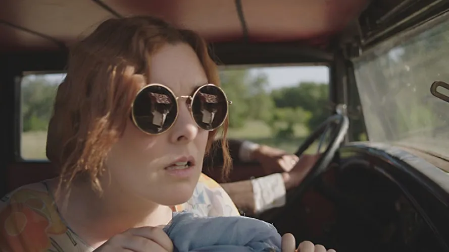 A woman looks out the window of a car.
