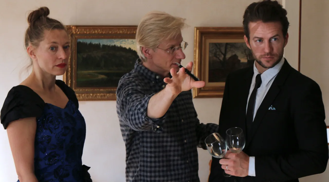 Man with raised hand talking to a man and a woman