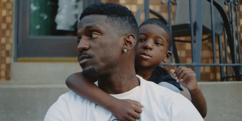 Man in white shirt with young child holding onto him from behind