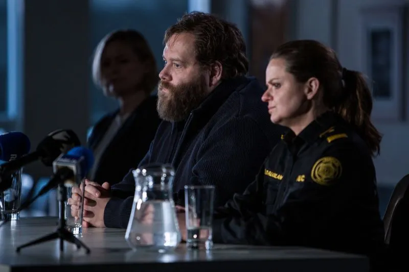 Three people sitting at a table with microphones