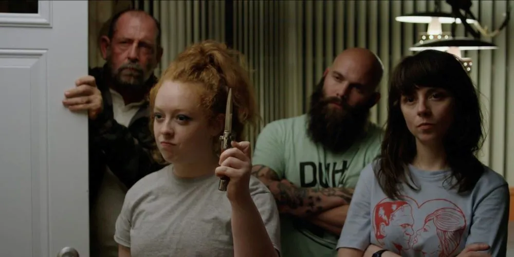 Four angry looking people, one is holding a blade