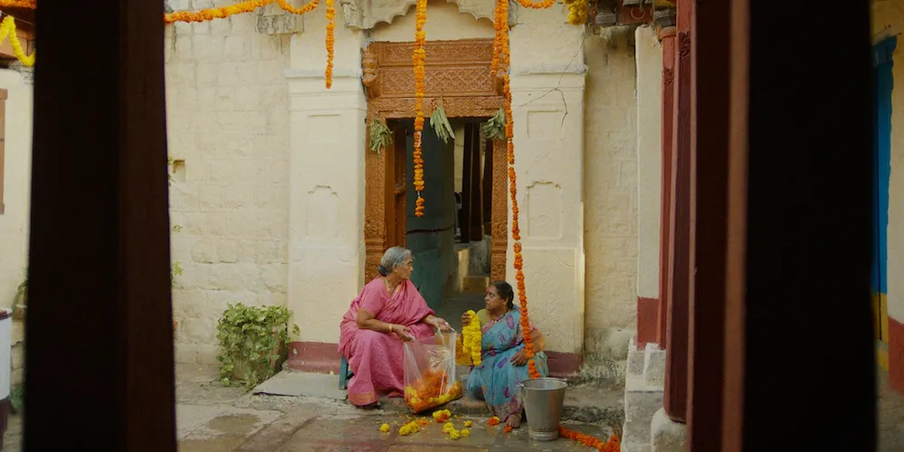 Two women sit in a courtyard