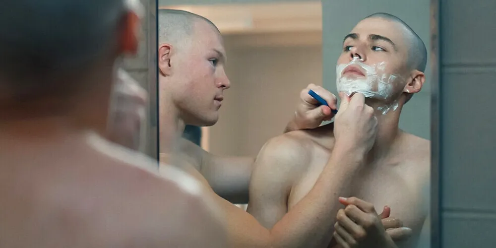 one man shaves another man's face