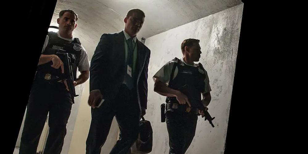 three men holding guns walk through a dark corridor