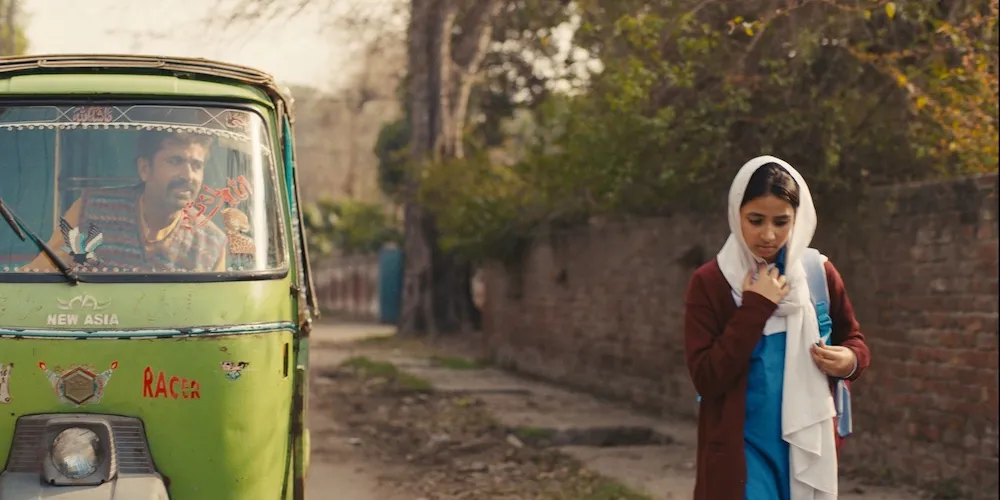 a man driving a bus drives next to a woman walking down the street