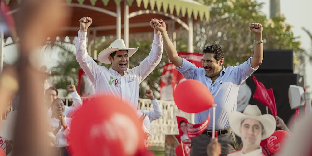 Two men cheer waving their arms in the air. 