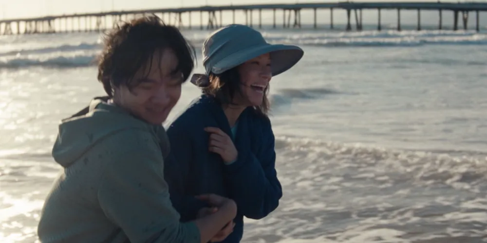 Two people stand by the ocean. 