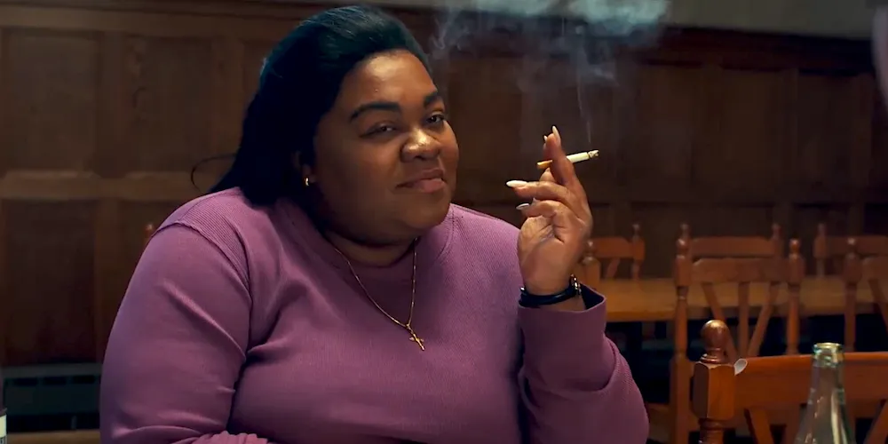 A woman sits holding a cigarette. 