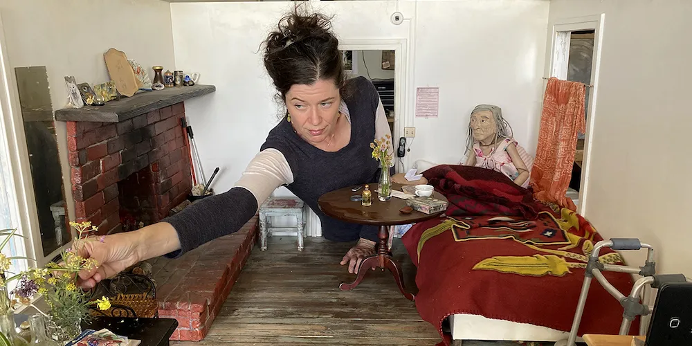 a person makes adjustments to a small-scale miniature room