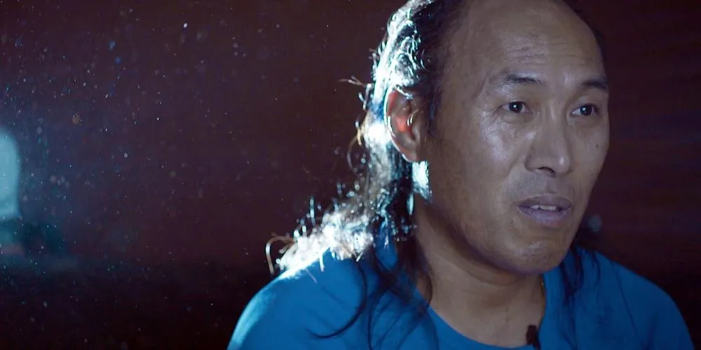 Still from 'Solastalgia'. A man stands under the rain.