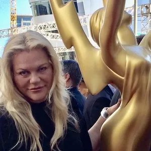 A woman stands next to a large yellow statue 