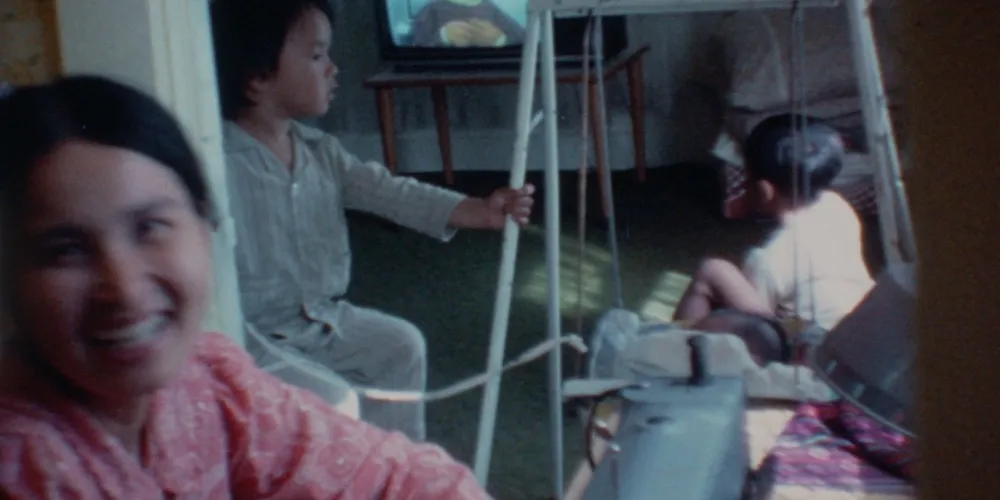Home footage of a young woman and two little boys in a living room