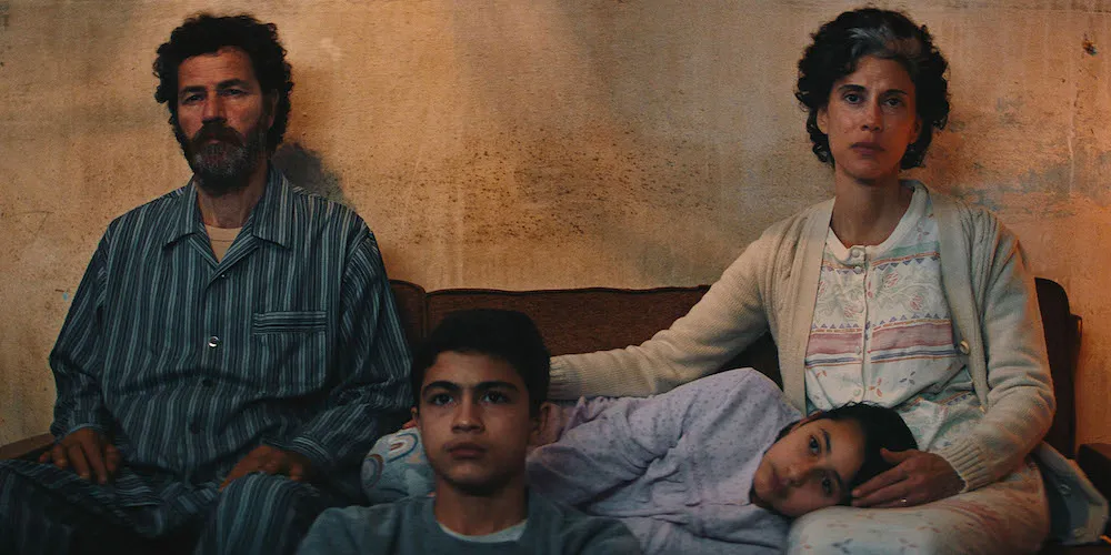 Two adults and two children sit on a couch. 