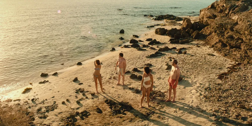 A group of people in swimsuits stand on a beach. 
