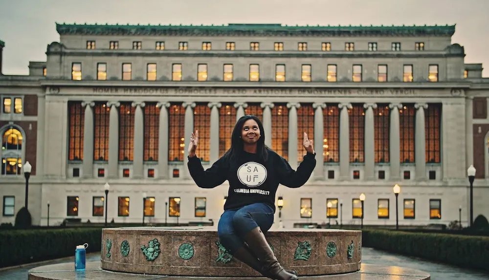 a woman sits outside a large university library