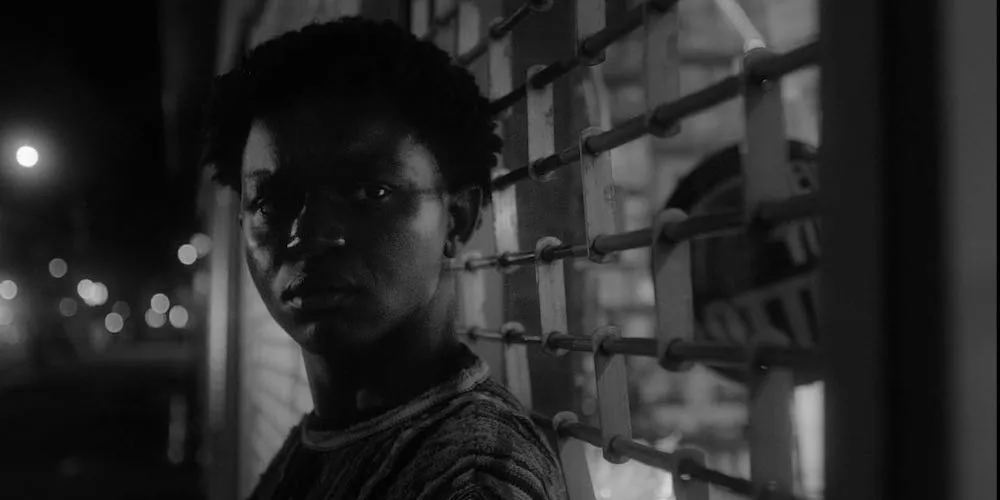 A boy stands against a grate