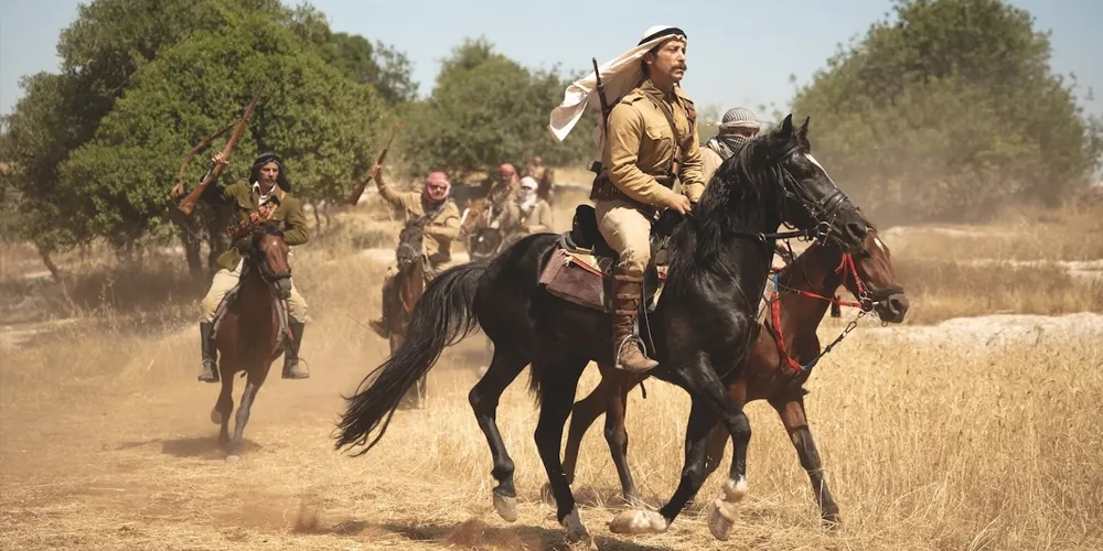 a group of men ride on horses, carrying weapons