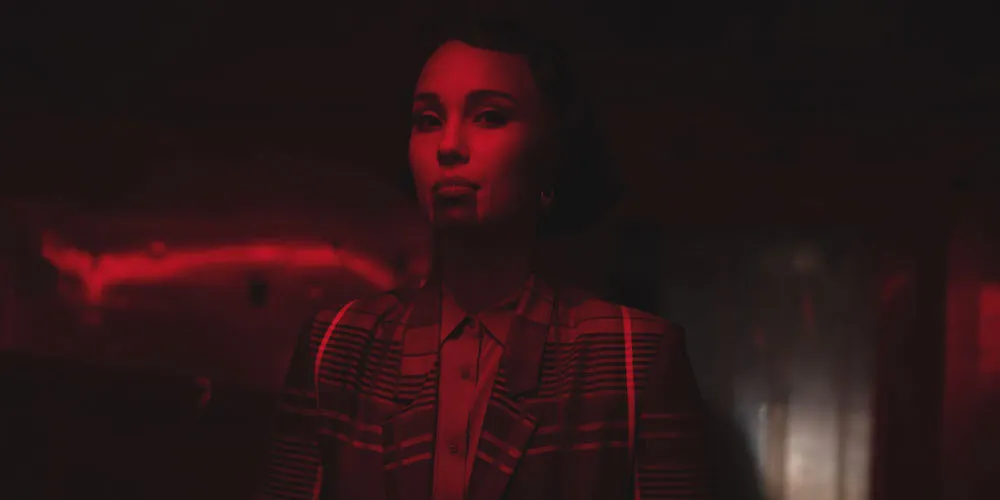 Woman stands under dark red lighting. 