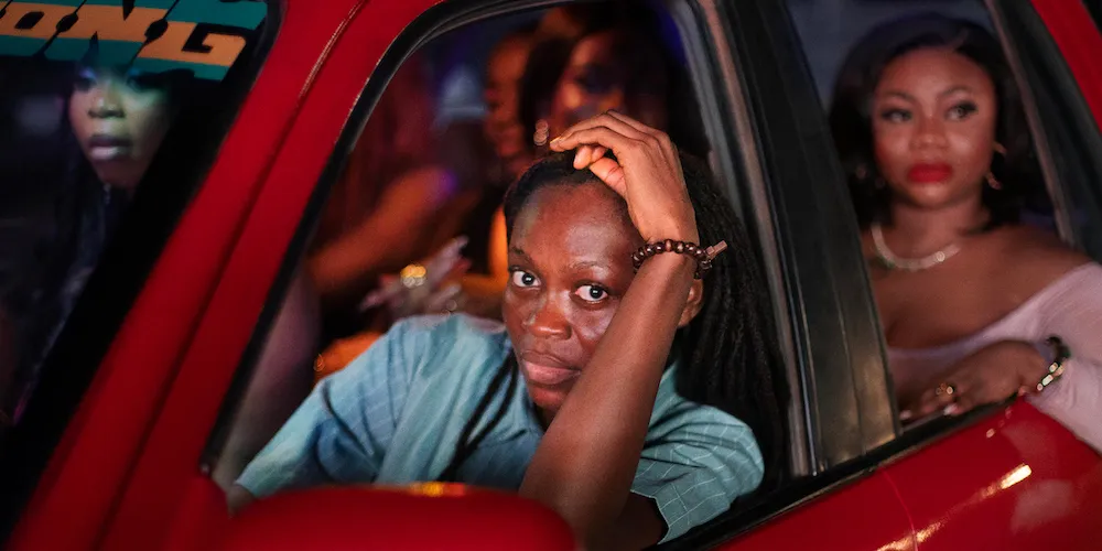 A group of women sit in a red car. 