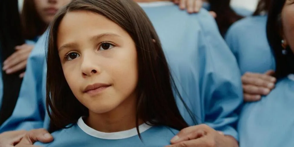close-up of a young girl standing in a crowd wearing blue