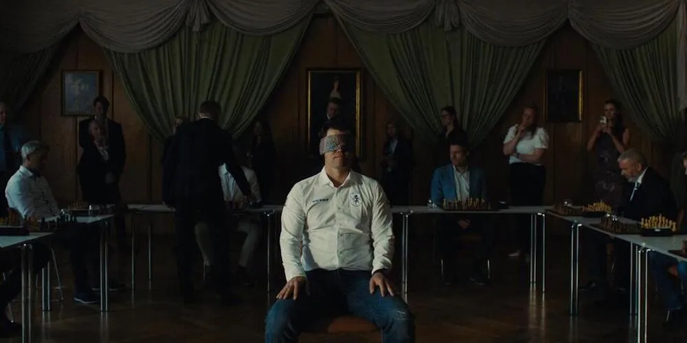 a man sits blindfolded in a room filled with people