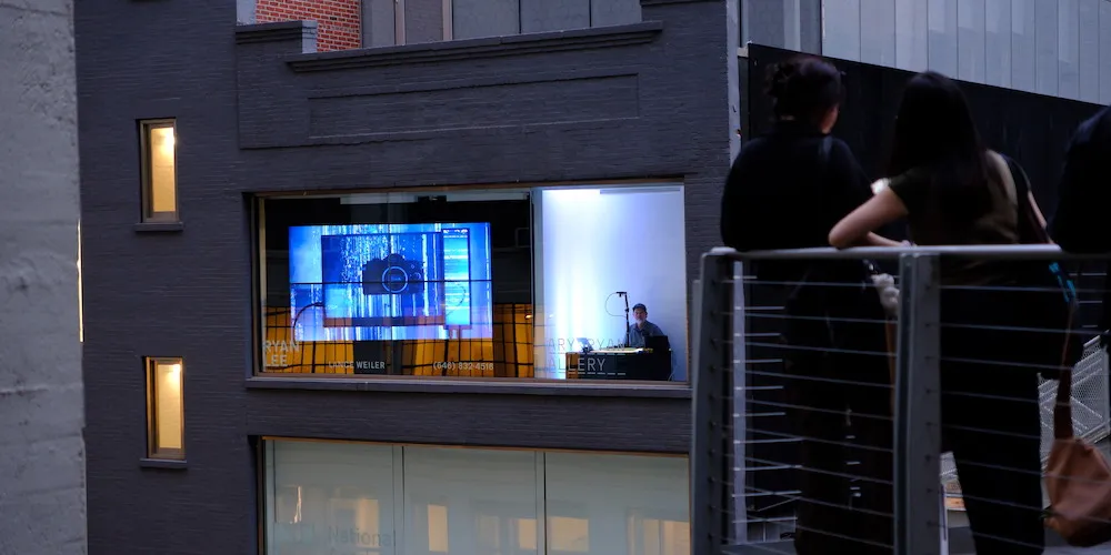 Viewers watch a live exhibition performance outside through the building's windows