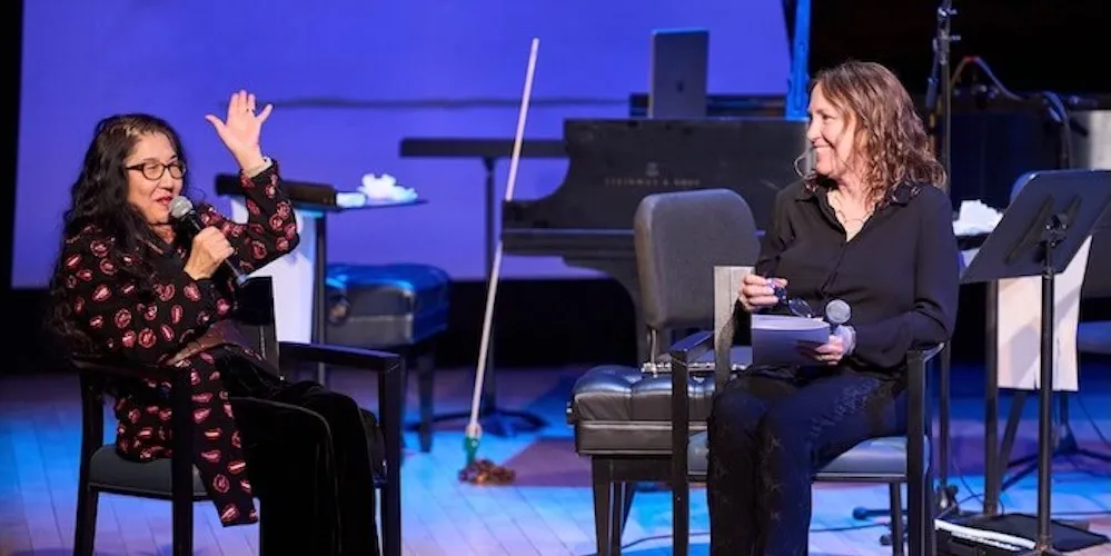 Two women sit on a stage