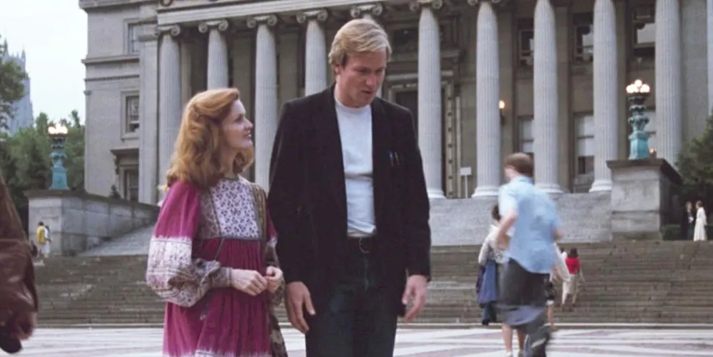 Two people walking in front of a white building with columns. 