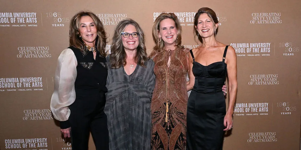Four women stand in front of a banner with the School of the Arts logo