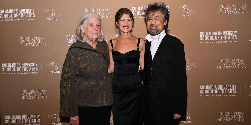three people in front of a banner with the School of the Arts logo