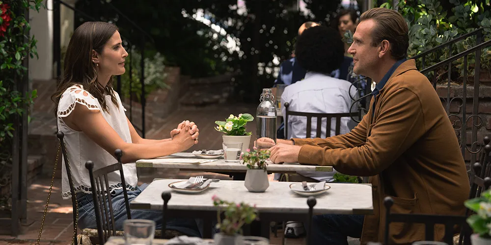 A woman and man sit together at an outdoor restaurant.