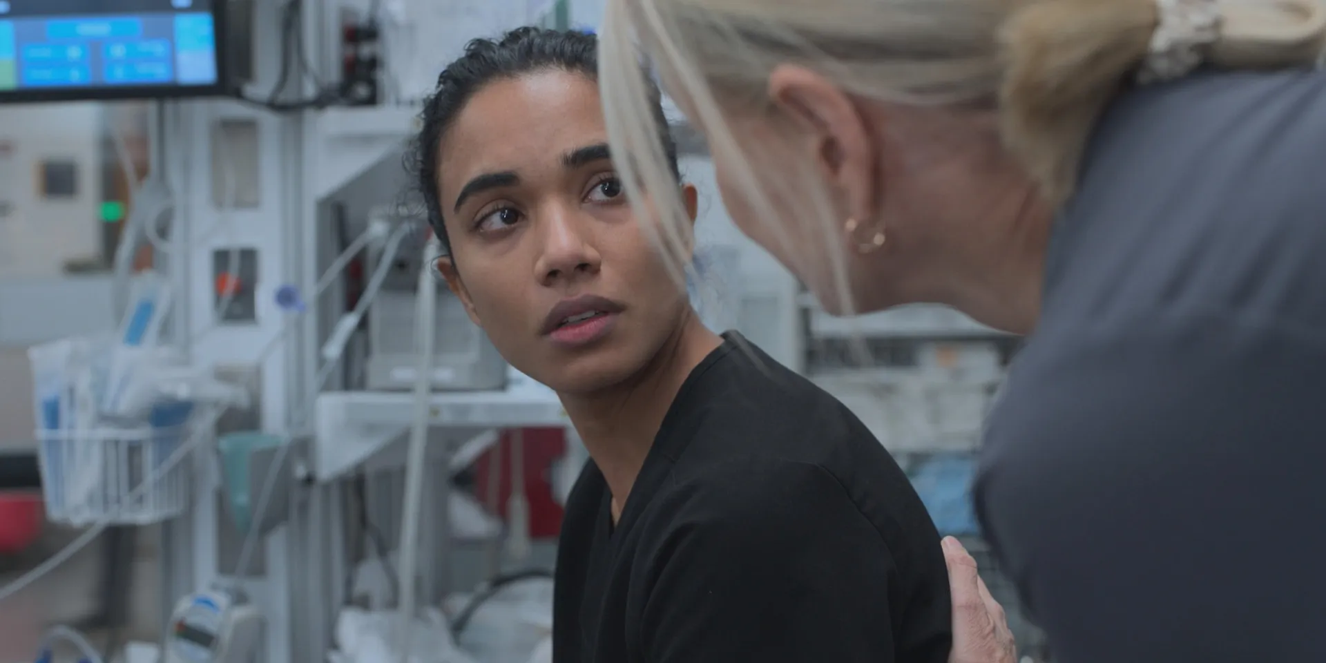 Two doctors talk to each other closely in a hospital.