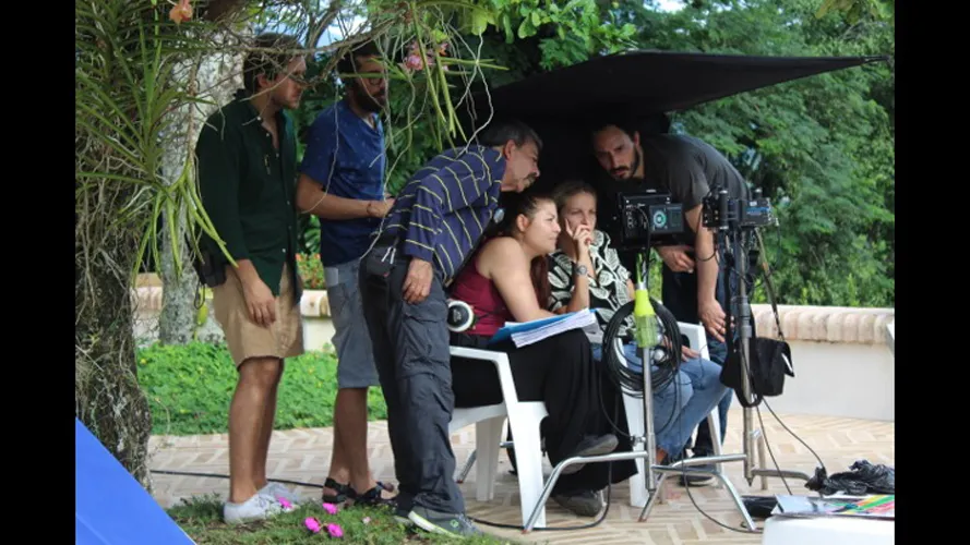 Behind the scenes of a film shoot. Group looks at monitor.