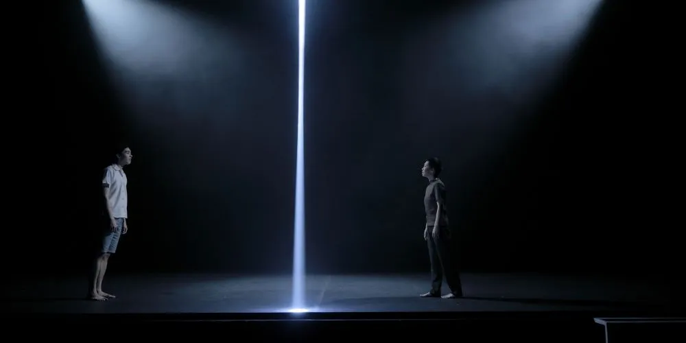 Two people on a stage with dramatic lighting