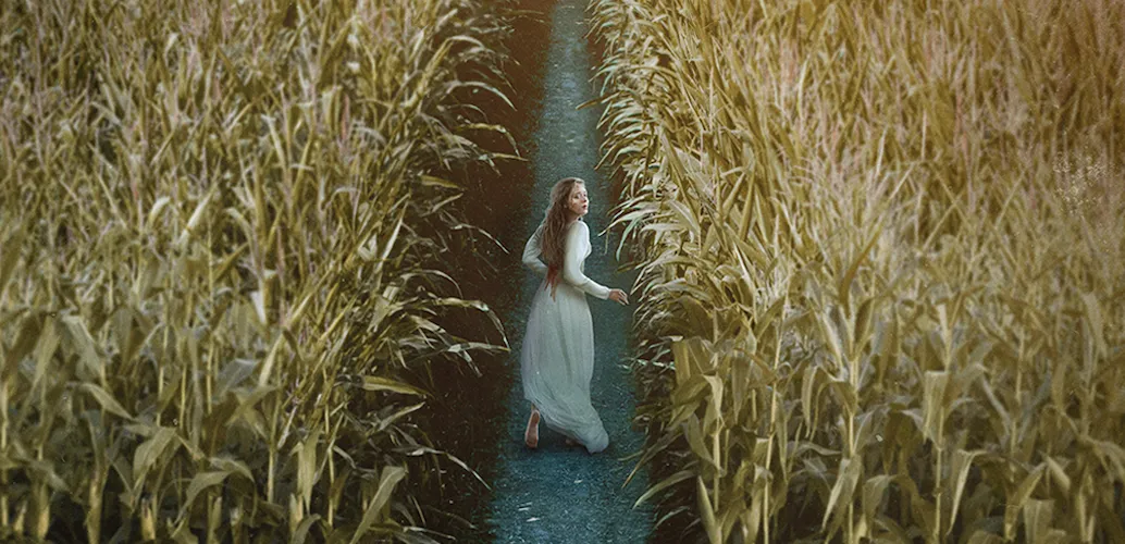 Woman in a white dress running through a corn field