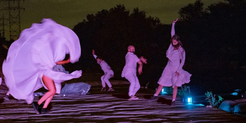 People in white dancing outside at night under blacklights