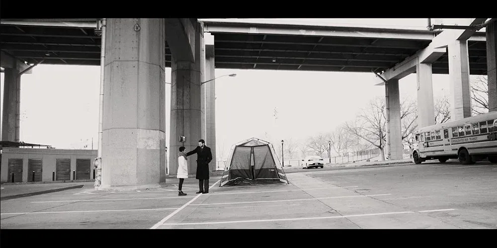 Black and white image of a man and a woman under a bridge.