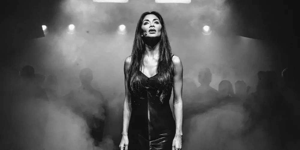 A woman stands on a stage full of mist. 