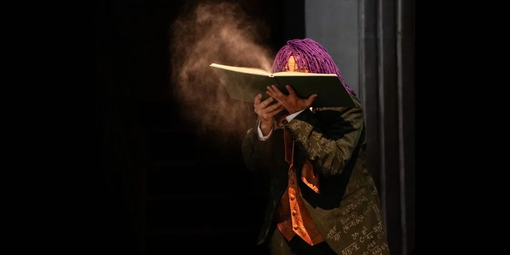 Actor holds book on stage.