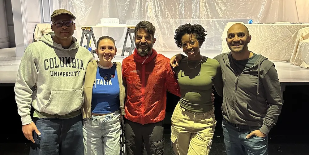 Five people stand in front of a stage. 